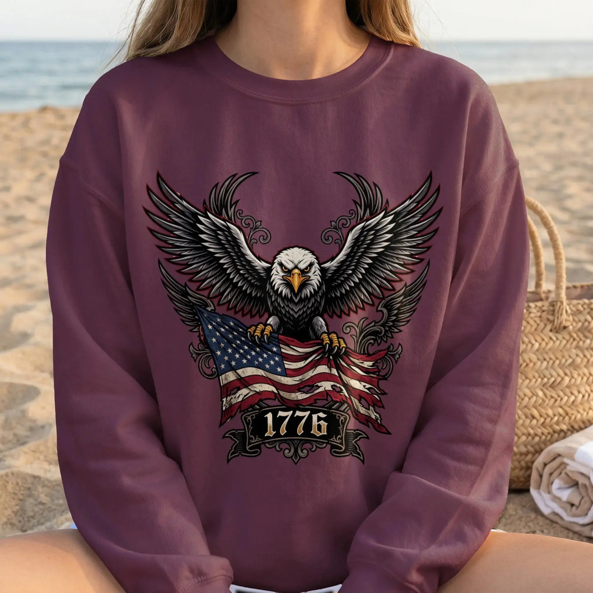 Eagle with outstretched wings holding American flag and "1776" on burgundy sweatshirt.